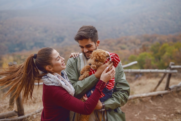 Linda pareja de pie en la naturaleza y jugando con su perro amoroso Foto Premium 