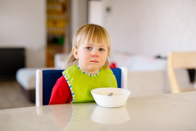 Lindo Bebe De 1 4 Anos Sentado En Una Silla Alta Para Ninos Y Comiendo Vegetales Solo En La Cocina Blanca Foto Premium