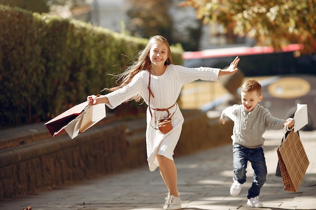 Lindos niños pequeños con bolsa de compras en una ciudad Foto gratis