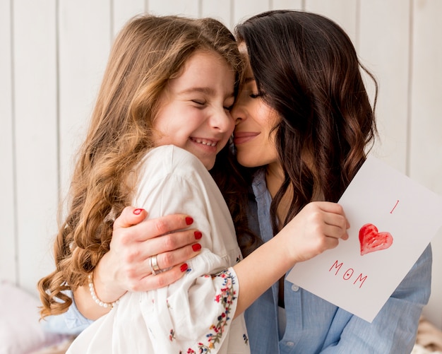 Madre abrazando a hija con tarjeta de felicitación | Foto Premium