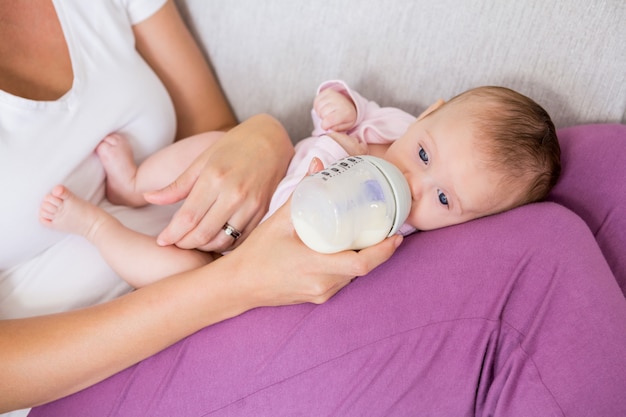 Madre Alimentando Al Bebe Con Biberon En La Sala De Estar Foto Premium