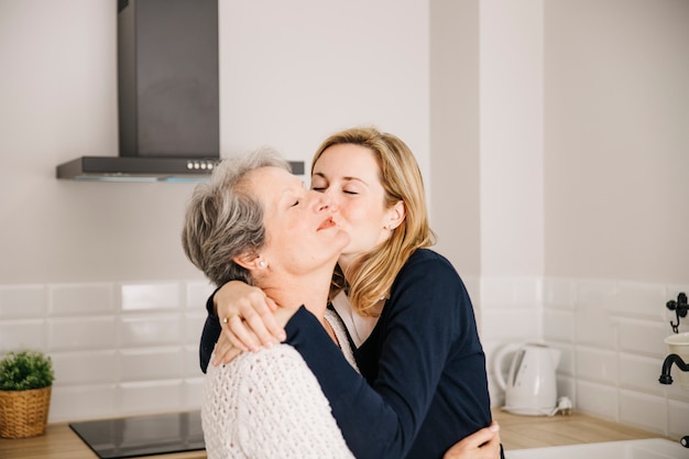 Madre besando hija en el día de la madre Foto gratis