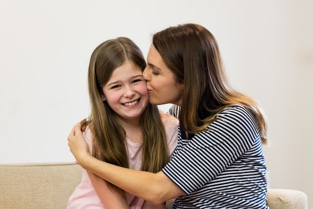 Madre besando a su hija en la sala | Foto Gratis