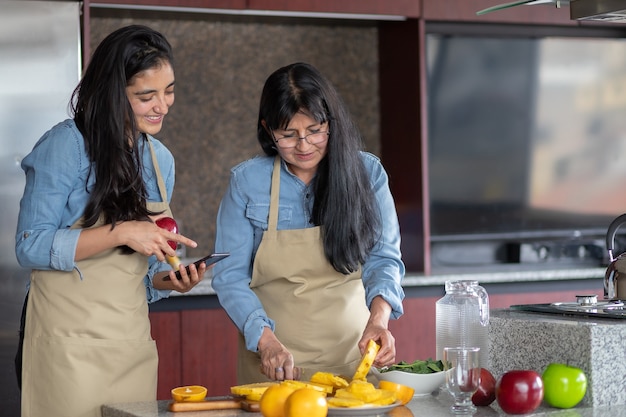 Madre E Hija Mexicana Cocinando En La Cocina Mirando La Receta En El Teléfono Inteligente Foto 