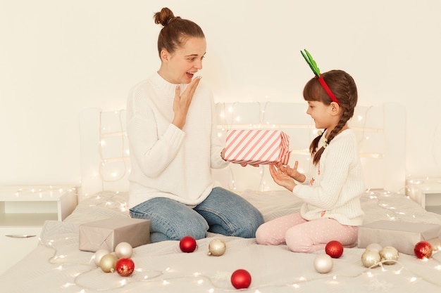 Madre E Hija Sorprendidas Vistiendo Su Teres Blancos De Estilo Casual Sentados En La Cama Ni O