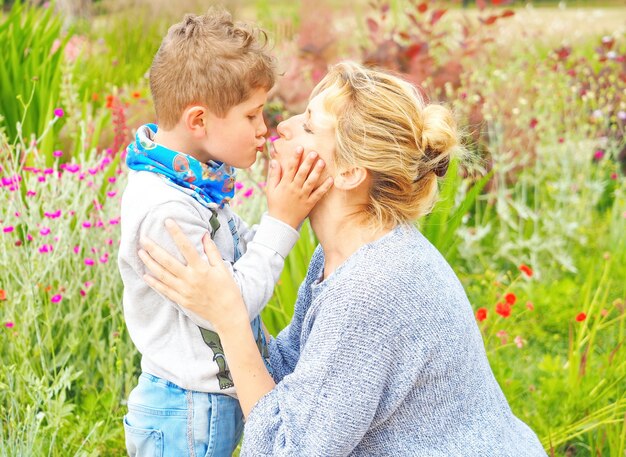 Madre E Hijo Se Abrazan Y Besan En El Jard N Con Flores Foto Premium