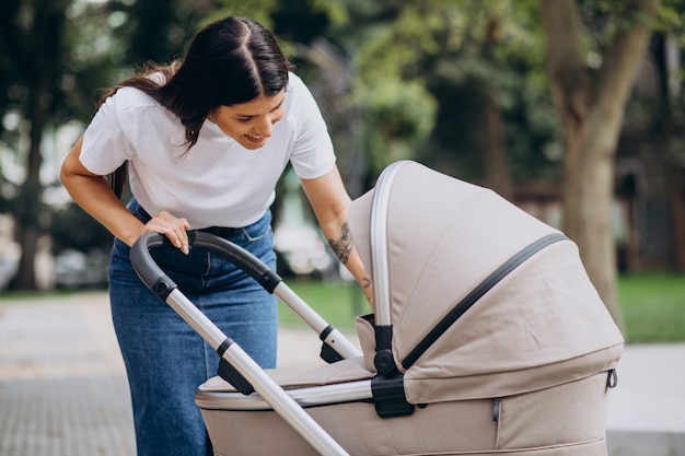 Madre Joven Caminando Con Cochecito De Bebé En El Parque | Foto Gratis