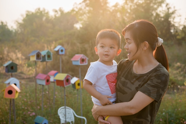 Madre joven feliz que juega y que se divierte con su pequeño hijo del bebé en el parque en un día de verano soleado Foto gratis