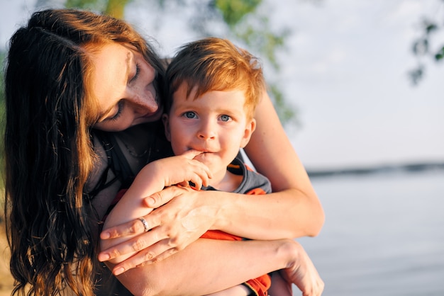 La Madre Sonriente Feliz Joven Sostiene A Su Hijo En Sus Brazos Y