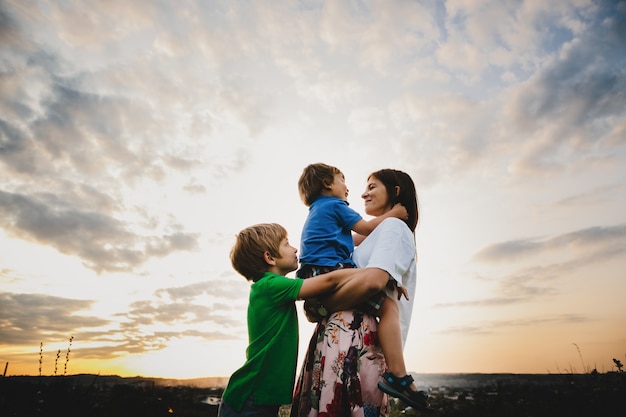 Mamá Abraza Con Sus Dos Pequeños Hijos Tiernos De Pie En Los Rayos Foto Gratis 