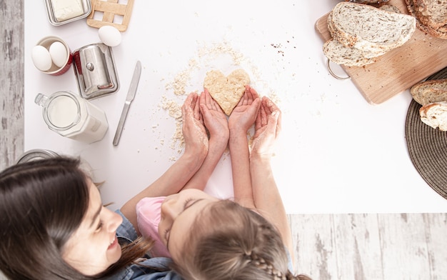 Mamá E Hija Están Preparando Galletas En Forma De Corazón En Una Gran Mesa De Cocina Blanca 