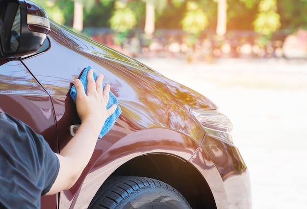 La mano del hombre es limpiar y encerar el coche. Foto gratis