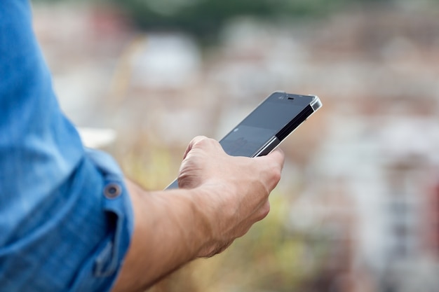 Mano Del Hombre Que Sostiene El Teléfono Móvil En La Ciudad Foto Gratis