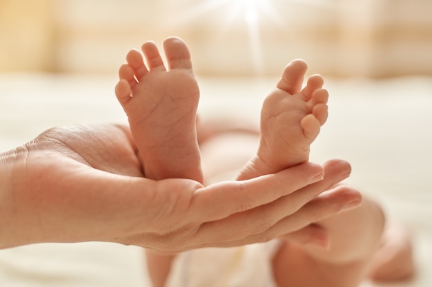 Mano De La Madre Que Sostiene Los Pies Descalzos Del Bebe Recien Nacido La Mama Hace Un Masaje Para El Bebe Para La Normalizacion Del Sistema Nervioso Y El Desarrollo De La