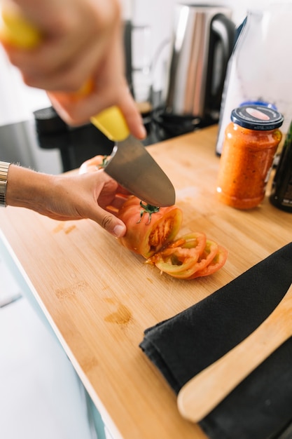 La Mano De Una Persona Cortando Rodajas De Tomate Con Un Cuchillo Afilado Foto Gratis