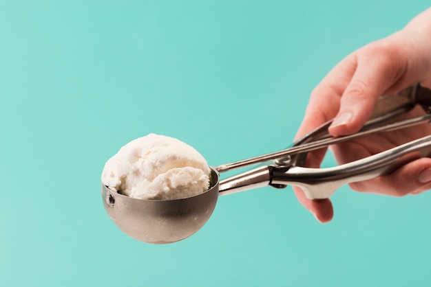 Mano que sostiene una cuchara de metal con sabroso helado de vainilla Foto gratis