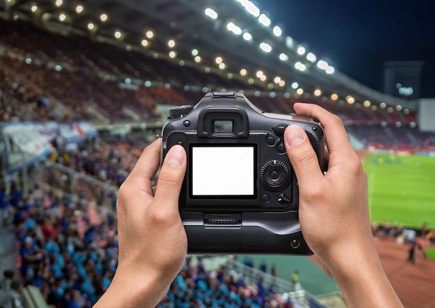 Mano Sosteniendo La Camara Sobre Resumen Foto Borrosa Multitud De Espectadores En Un Estadio Foto Premium