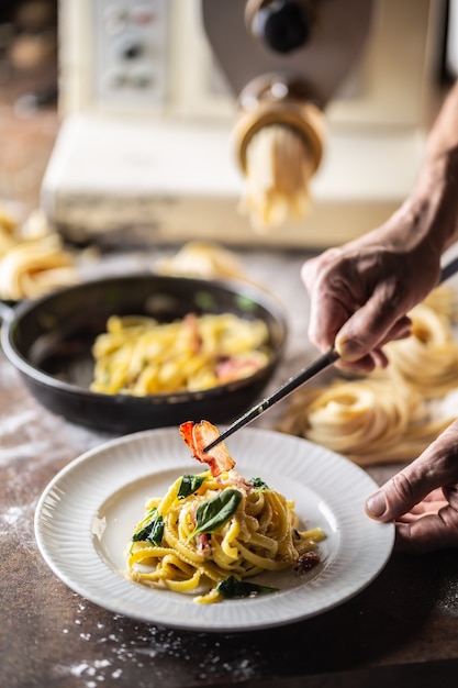 Manos de chef chapado en pasta recién hecha con una máquina para hacer