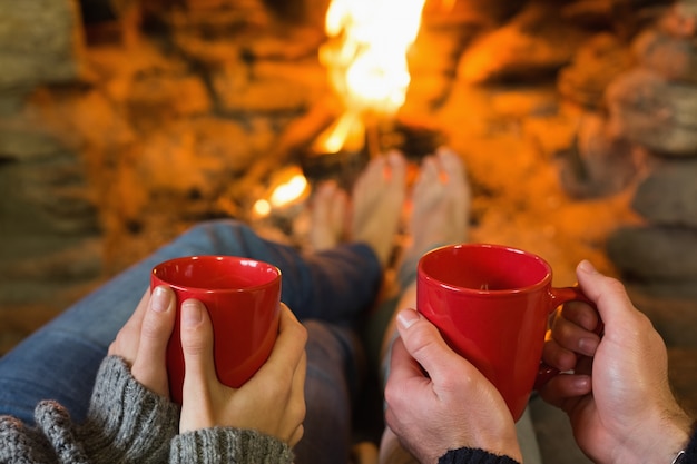 manos-con-tazas-de-cafe-rojas-frente-a-la-chimenea-encendida_13339-42035.jpg