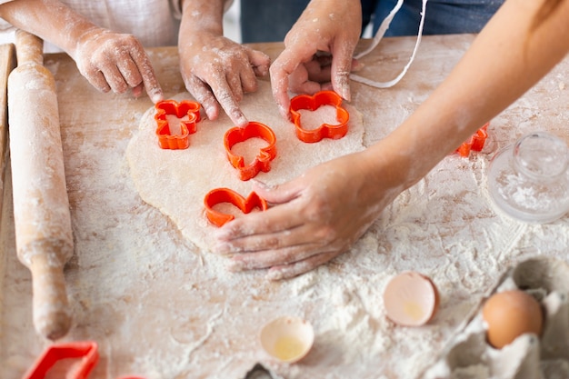 Manos cortando masa con formas de galleta Foto gratis
