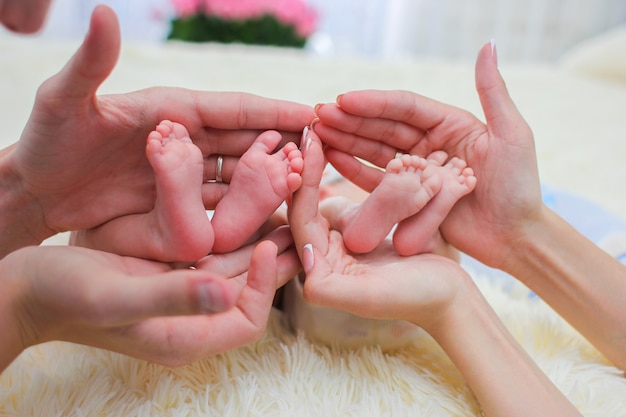 Las Manos De Mama Y Papa Sostienen Pequenas Piernas De Sus Dos Bebes Gemelos Recien Nacidos Foto Premium