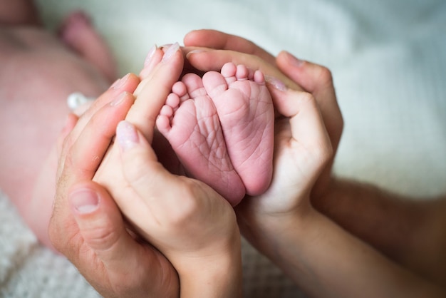 Las Manos De Mama Y Papa Sostienen Las Piernas Del Bebe Foto Premium