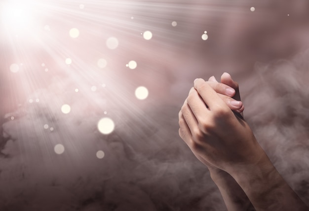 Manos masculinas en posición de oración con ray Foto Premium