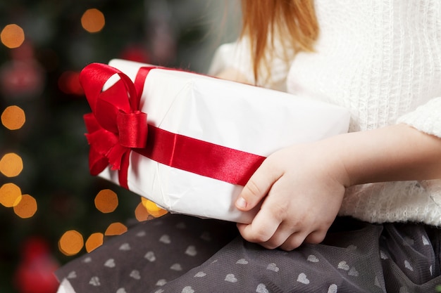 Manos del niño con caja de regalo. navidad, año nuevo, concepto de cumpleaños. fondo festivo con bokeh y luz solar. cuento de hadas mágico Foto Premium