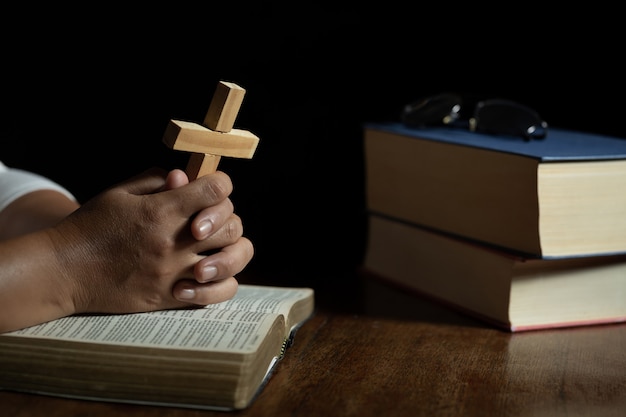 Manos rezando a dios mientras sostiene el símbolo de la cruz. Foto gratis