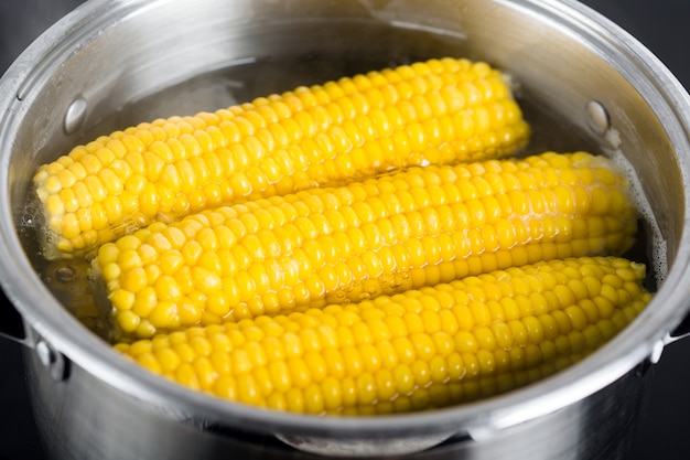 La mazorca de maíz hervida en una olla de agua hirviendo | Foto Premium