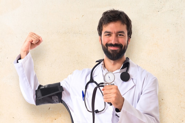 Médico fuerte con monitor de presión arterial sobre fondo blanco Foto gratis