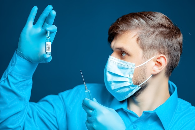 Un médico con máscara médica y guantes vestido con un uniforme azul