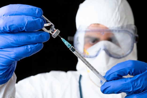 Médico o científico en el uniforme de la suite de epp en el laboratorio  sostenga el frasco y la jeringa de la vacuna líquida de la medicina | Foto  Premium