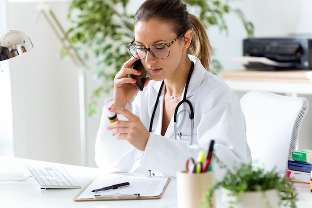 Médico usando su teléfono móvil en la oficina. | Foto Premium