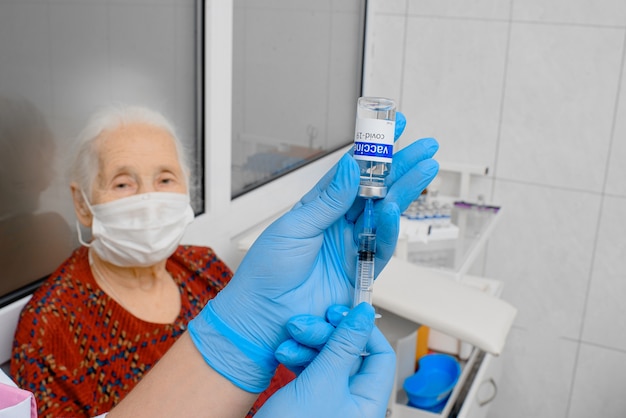 Médico vacuna a una anciana con una mascarilla quirúrgica Foto Premium 