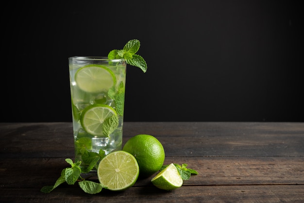 Mojito de bebida con lima, limón y menta en mesa de madera. Foto gratis