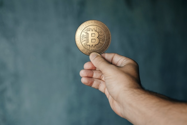 Moneda de oro bitcoin en la mano. el concepto de moneda criptográfica. tecnología blockchain ...