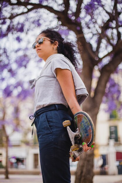 Morena adolescente niña tenencia patín posición afuera Foto Gratis