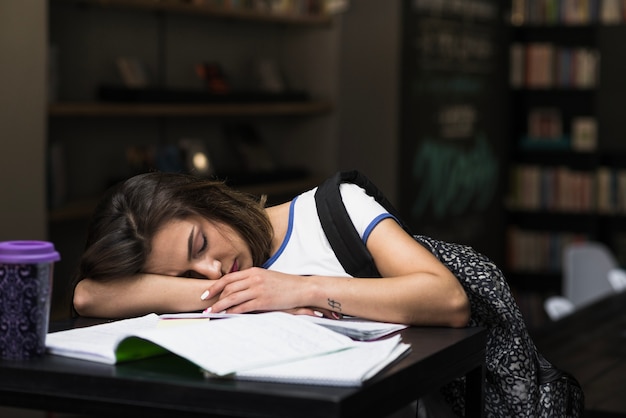 Morena Chica Durmiendo Apoyándose En La Mesa Foto Gratis 