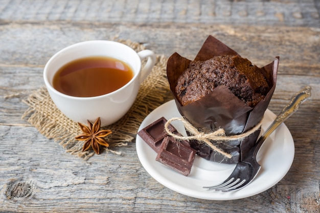 Muffin de chocolate y una taza de café sobre una superficie de madera