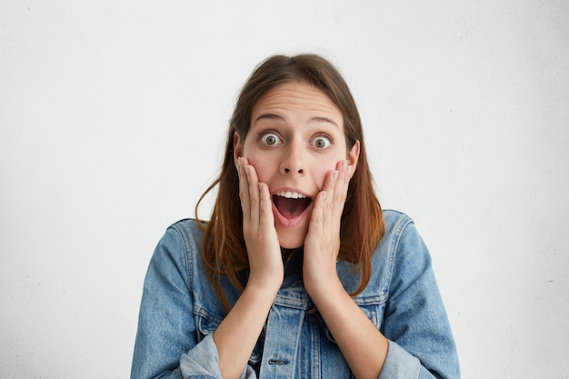 Mujer Agradablemente Sorprendida Mirando Con Ojos Saltones Cogidos De La Mano En Las Mejillas