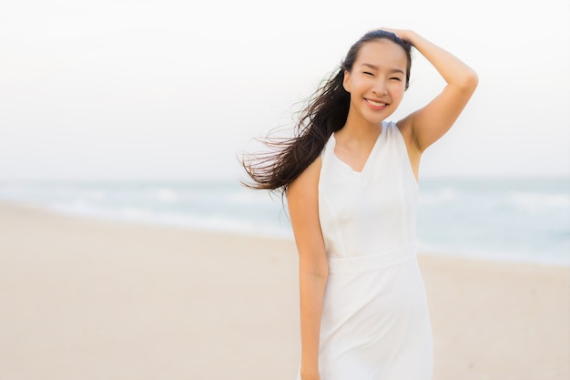 Mujer asiática joven hermosa del retrato feliz y sonrisa en el mar y el océano de la playa Foto gratis