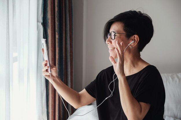 Mujer asiática de mediana edad haciendo videollamadas en casa | Foto