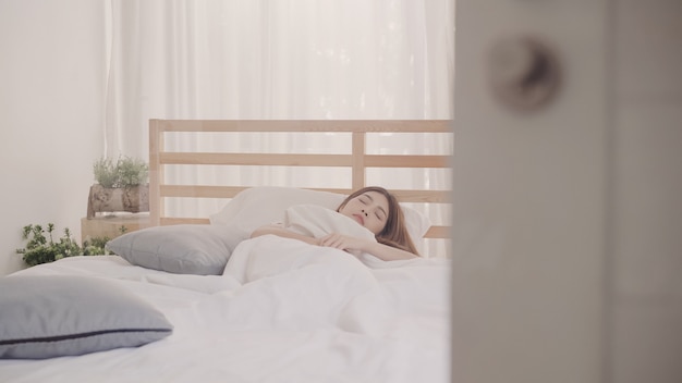 Mujer asiática soñando mientras dormía en la cama en el dormitorio Foto gratis