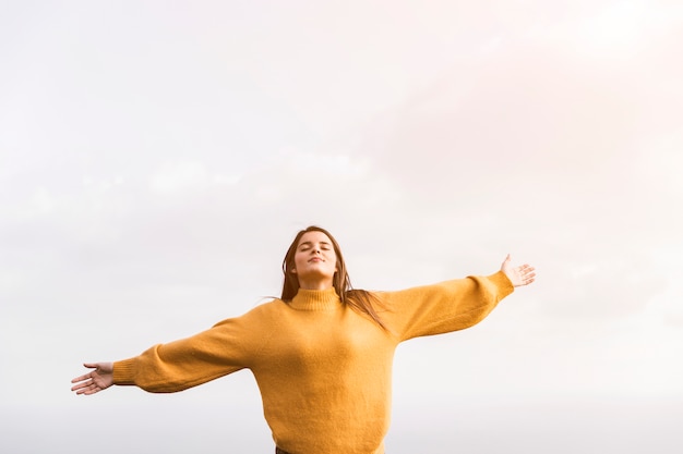 Una mujer caminante con los brazos extendidos disfrutando del aire fresco contra el cielo. Foto gratis