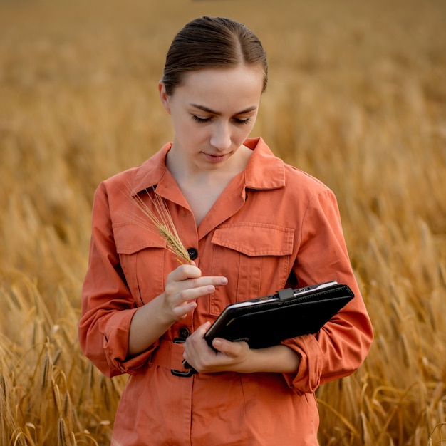 Mujer caucásica tecnólogo agrónomo con tablet pc en el campo de trigo