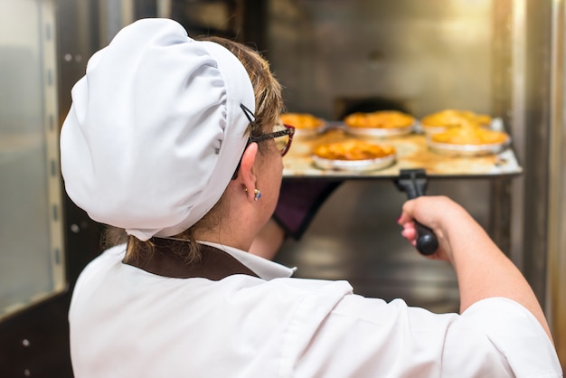 Mujer En La Cocina De Una Panadería Cocinando Pasteles En Un Horno Foto Premium 