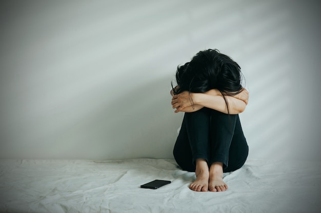La Mujer De La Depresión Abraza Su Rodilla Y Llora Triste Mujer Sentada Sola Con Un Teléfono A