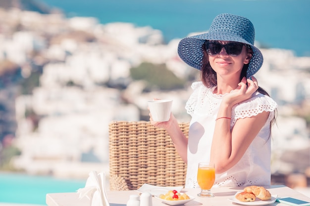 Mujer desayunando en un café al aire libre con una vista increíble de la ciudad de mykonos. Foto Premium