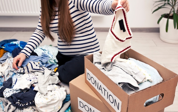 Mujer Embarazada Esta Clasificando Ropa De Bebe Y Quiere Donar Algunas Cosas A La Caridad Foto Premium